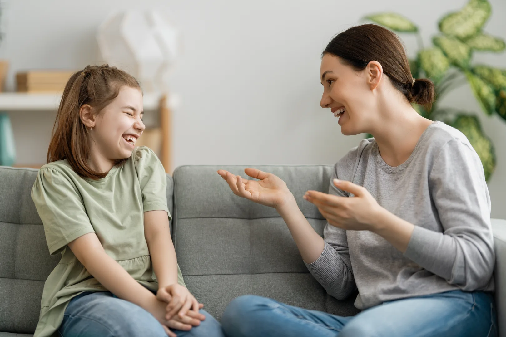 Anne ve kızı koltukta oturarak gülümseyerek sohbet ediyor