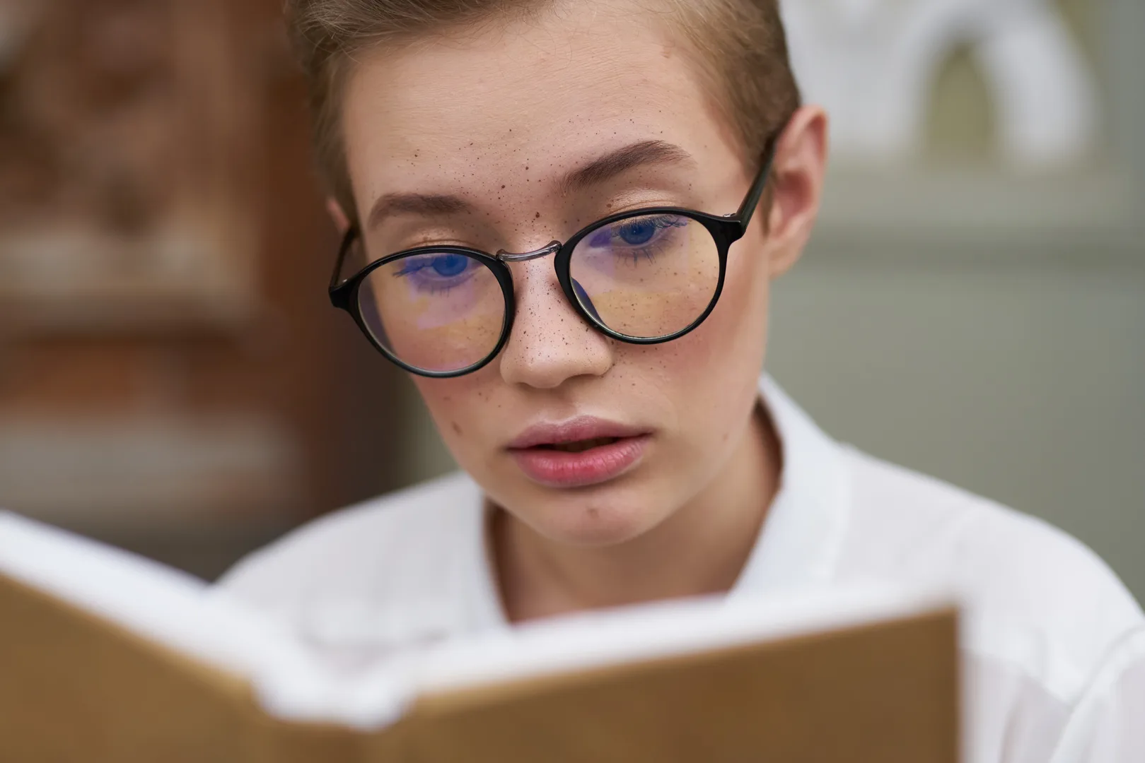 Gözlüklü genç kız öğrenci dikkatle kitap okurken